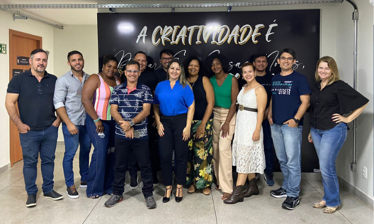 Um grupo de empreenderores posuando para a foto em frente a um painel criativo. 